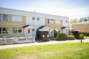 Ein modernes Mehrfamilienhaus mit flachem Dach, befahrtshemmender Einfahrt und gepflegtem Rasen.