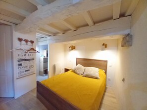 Un dormitorio con una cama de madera, una colcha amarilla y un radiador blanco.