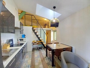 Eine moderne Küche mit eingebauter Mikrowelle, ein Essbereich mit Tisch und Stühlen sowie eine Treppe zu einer oberen Ebene.