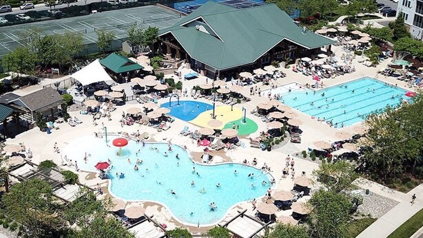 Um resort com várias piscinas, áreas de descanso e quadra de tênis.