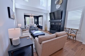 A modern living room with a fireplace, comfortable seating, and a large TV.