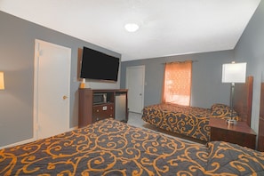 Una habitación de hotel con dos camas, televisión, escritorio y espejo.