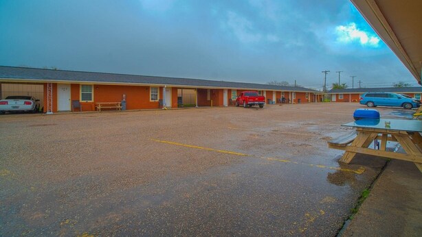 A motel with a parking lot, a red truck, and a blue car. - 2 Queen Beds|Smk|Kitchenette (Houston)