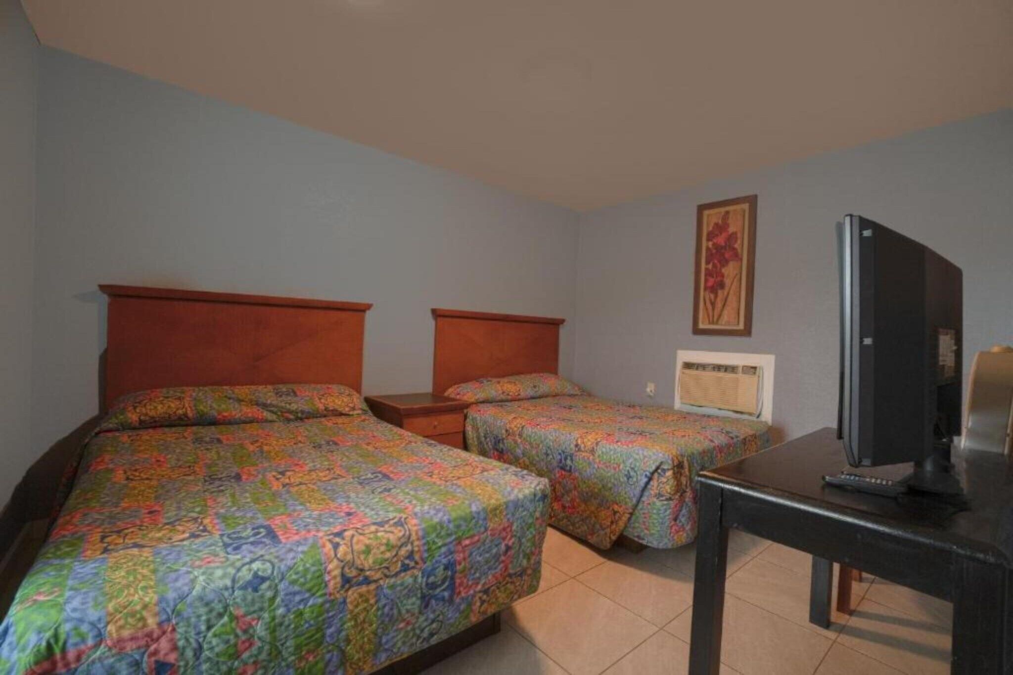 Una habitación de hotel con dos camas, un televisor y una mesita.