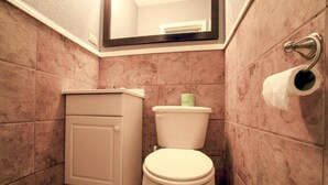 A bathroom with a toilet, a cabinet, and a towel rack. - 3 Queen Beds|Smoking (Houston)