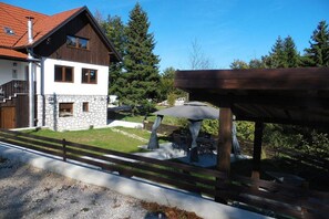 Ein zweistöckiges Haus mit Steinverkleidung, einer Holzterrasse und einem überdachten Sitzbereich im Freien.
