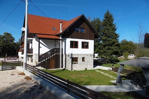 Ein zweistöckiges Gebäude mit einer Steinaußenwand, einem roten Ziegeldach und einer Treppe, die zum Obergeschoss führt.