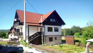 Ein zweigeschossiges Haus mit rotem Ziegeldach, einer Steinaußenwand und einer Treppe, die zum oberen Stockwerk führt.