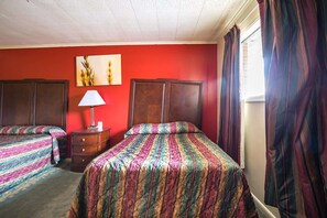 A hotel room with two beds, a dresser, a lamp, and a window with curtains. - 2 Full Bed Smoking | Holly Springs MS (Holly Springs MS)