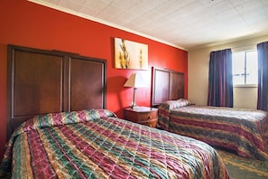 A hotel room with two beds, a nightstand, a lamp, and a window with curtains. - 2 Full Bed Smoking | Holly Springs MS (Holly Springs MS)