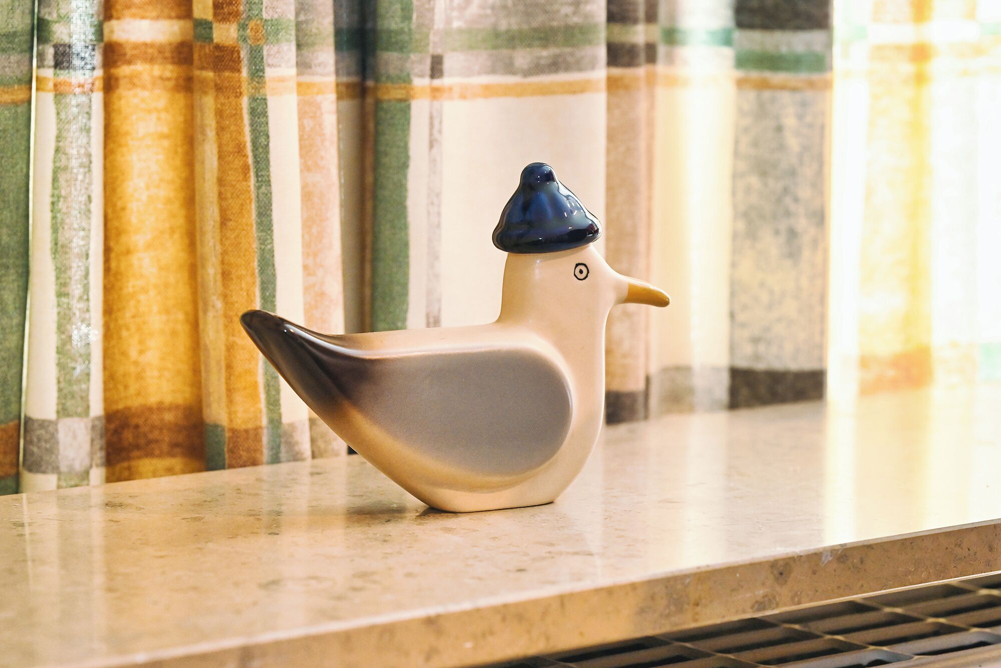 Una statuina di ceramica a forma di uccello su una superficie in marmo.