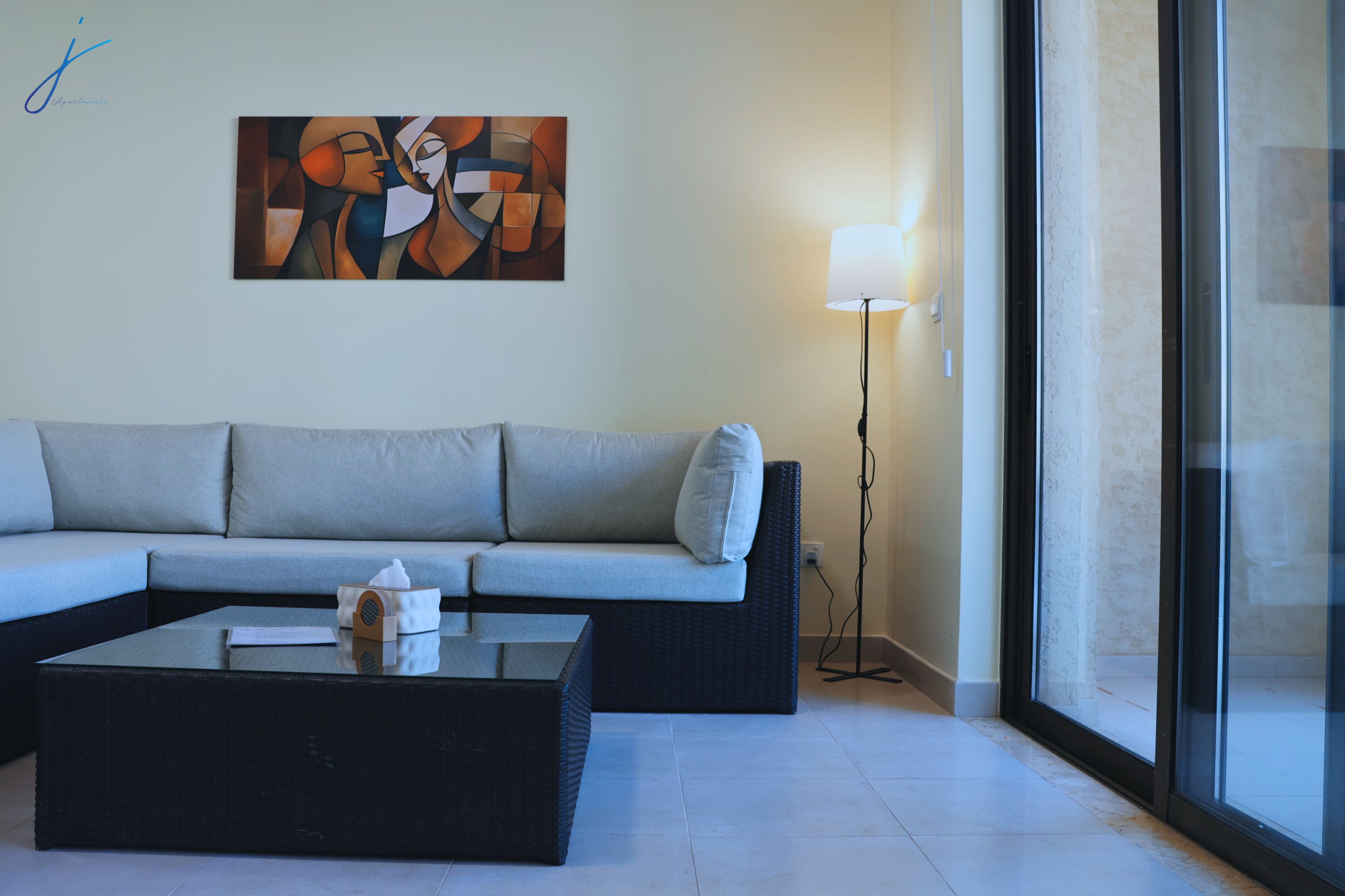 Una sala moderna con un sofá, una mesita de centro, una lámpara y un cuadro en la pared.