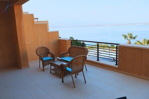 A balcony with wicker furniture and a view of the sea.