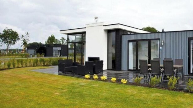 Une maison moderne dotée d’un patio, d’un espace salon extérieur et d’une pelouse bien entretenue.