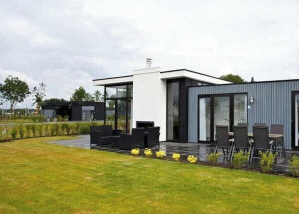 A modern house with a patio area, outdoor seating, and a well-maintained lawn. - Cube Exclusive 6 (Nijkerk)