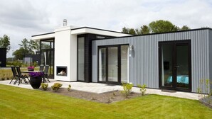 Une maison moderne à deux étages, dotée d’une terrasse, d’un petit jardin et d’une piscine.