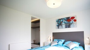 Une chambre à coucher comprenant un lit, une table de chevet, un tableau et une porte donnant sur une salle de bain.