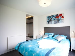 A bedroom with a bed, a nightstand, a painting, and a door leading to a bathroom. - Cube Exclusive 6 (Nijkerk)