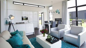 Un salon moderne avec un canapé, une table basse et des fauteuils. Il y a également un coin cuisine équipé de placards et d’appareils électroménagers.