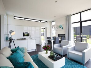 A modern living room with a sofa, coffee table, and chairs. There is a kitchen area with cabinets and appliances. - Cube Exclusive 6 (Nijkerk)