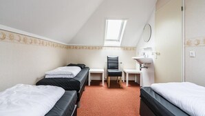 A room with two beds, a desk, a chair, a mirror, and a window.