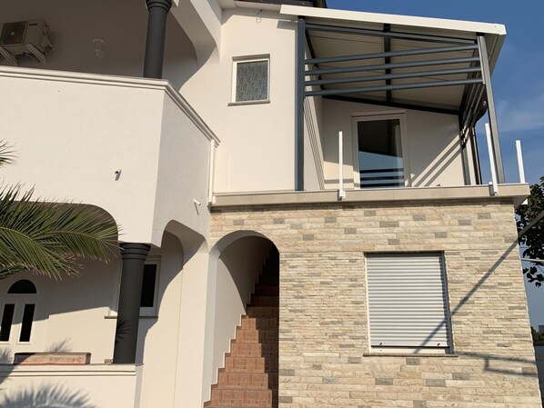 A modern two-story building with a stone facade, a balcony with metal railings, and a staircase leading to the upper level. - Studio Apartment Vir 2 (Vir)