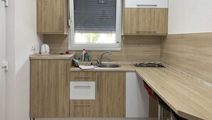 Cozinha compacta com armários de madeira, uma janela com persianas, uma pia e um fogão.