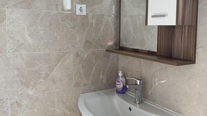 Casa de banho com uma pia branca, um espelho em cima e um frasco de sabonete nas bancadas.