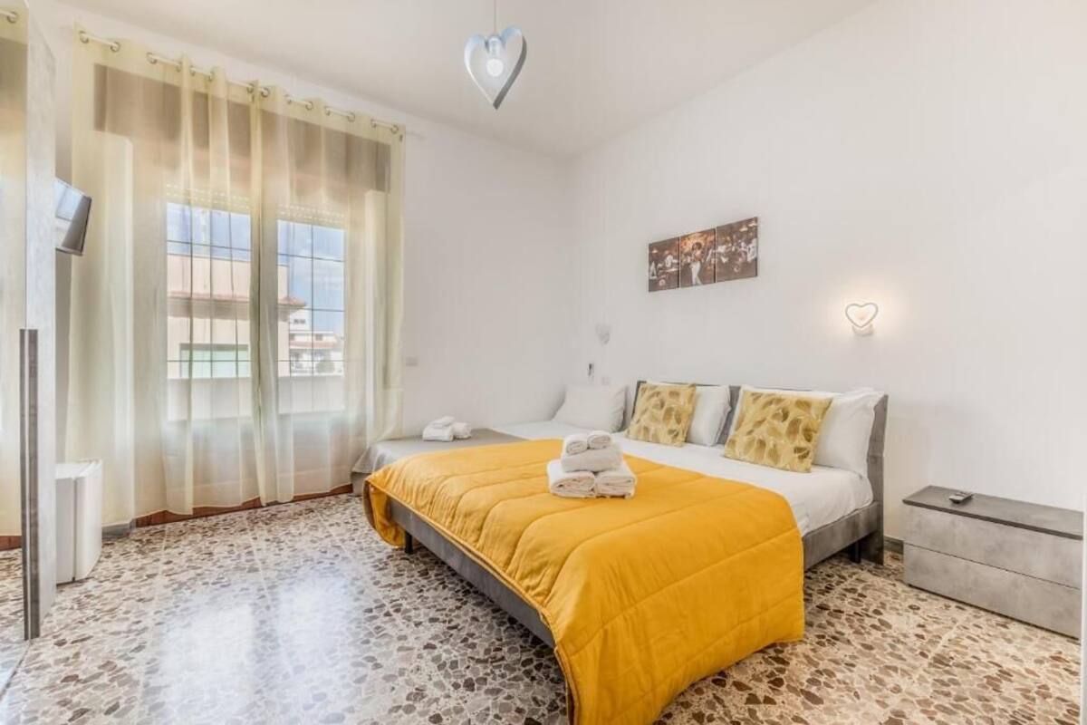Un dormitorio con una cama, una mesita de noche, una lámpara de pared, un cuadro y una lámpara en forma de corazón.