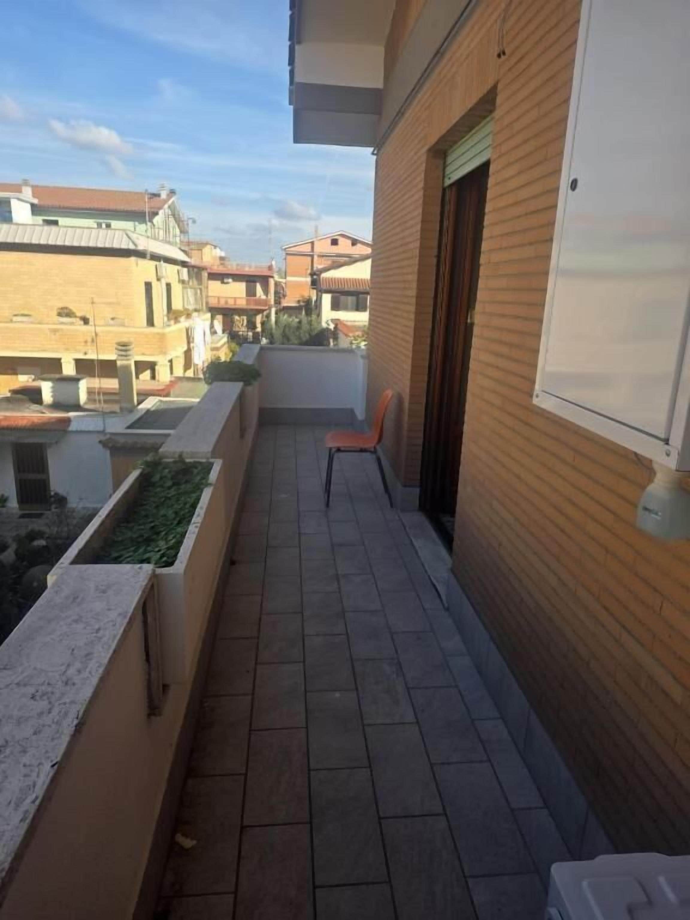 Un balcone con pavimento in piastrelle, parete in legno e porta bianca.