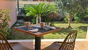 An outdoor patio with a table set for two, surrounded by chairs, with a garden view. - THAT'S LOVE JAZZ FIUMICINO (Fiumicino)