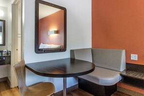 A hotel room with a round table, two chairs, a sofa, a mirror, and a wall-mounted light fixture. - 1 King Bed | Smoking, Micfridge (Fresno)