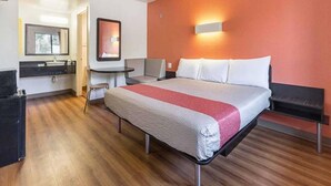 A hotel room with a bed, a desk, a chair, a small table, and a mirror. - 1 King Bed | Smoking, Micfridge (Fresno)