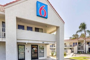 A motel with a prominent '6' sign, a covered entrance, and a two-story building with balconies. - 1 King Bed | Smoking, Micfridge (Fresno)