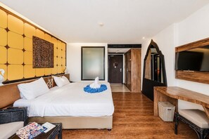 Quarto de hotel com uma cama, escrivaninha, televisão e um espelho grande.