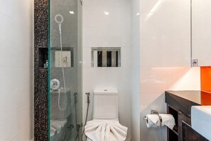 Uma casa de banho moderna com chuveiro em cabine de vidro, sanita e lavatório com barra de toalhas.