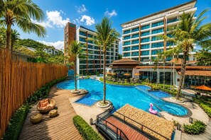 Um hotel com uma piscina grande, palmeiras e um deck de madeira.
