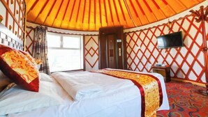 A yurt with a bed, a television, and a window.