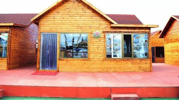 A wooden cabin-style building with a pitched roof, large windows, and a visible door.