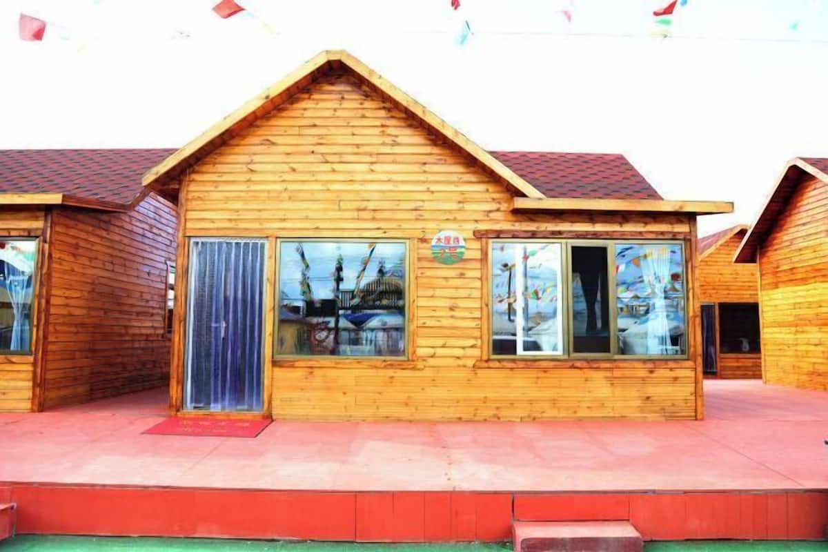 Una cabaña de estilo rústico con techo a dos aguas, ventanas grandes y una puerta visible.