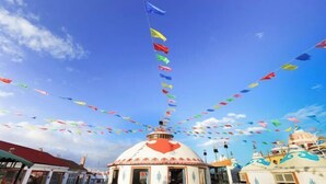 A building with a dome and a flagpole, surrounded by colorful flags.