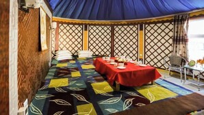 A dining area with a table set for four, a patterned carpet, and a blue tent-like structure overhead.
