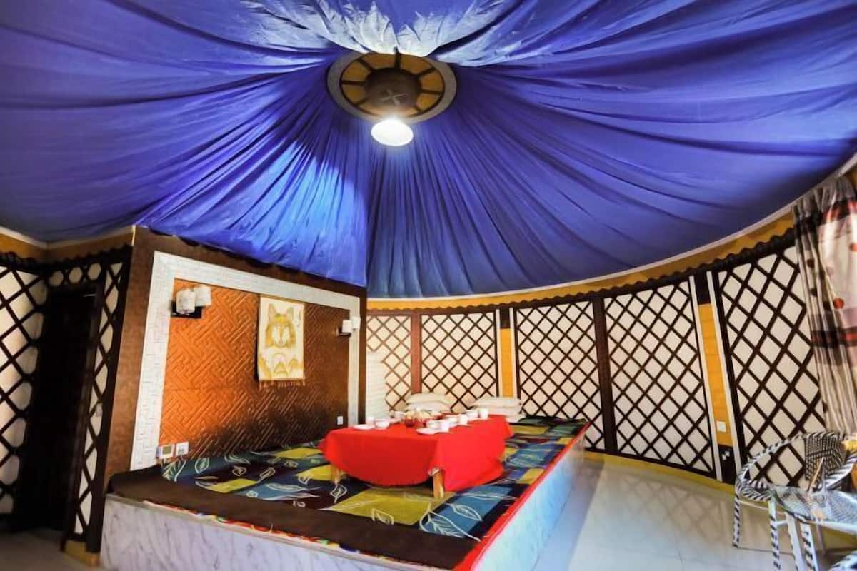 Una habitación con una cama, un sofá rojo, un ventilador de techo y un adorno en la pared.