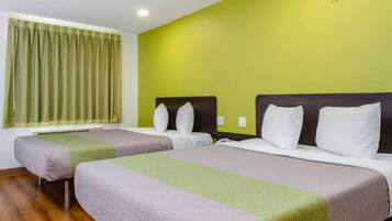 Une chambre d’hôtel avec deux lits, un mur vert et une fenêtre avec des rideaux.