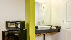 Une petite cuisine équipée d’un four à micro-ondes, d’un évier et d’un miroir.