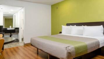 A hotel room with a bed, a desk, a chair, and a mirror.
