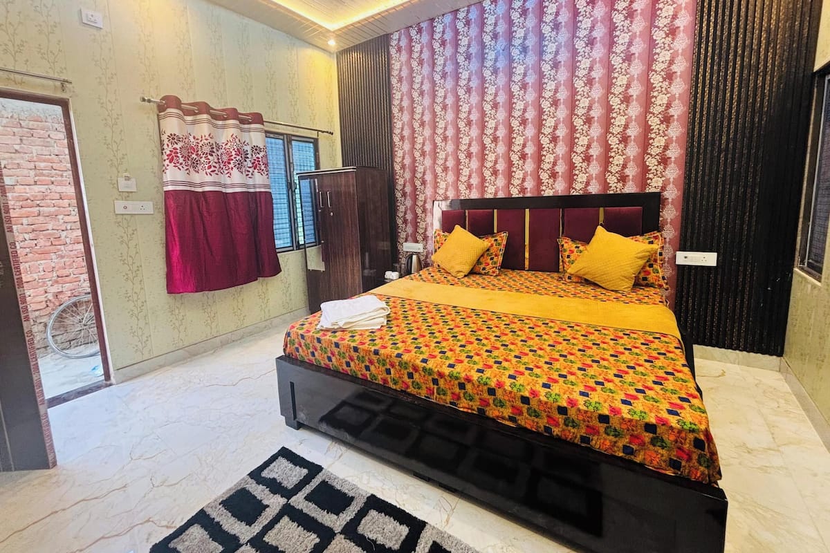 Un dormitorio con cama, cortinas, armario y una alfombra estampada.