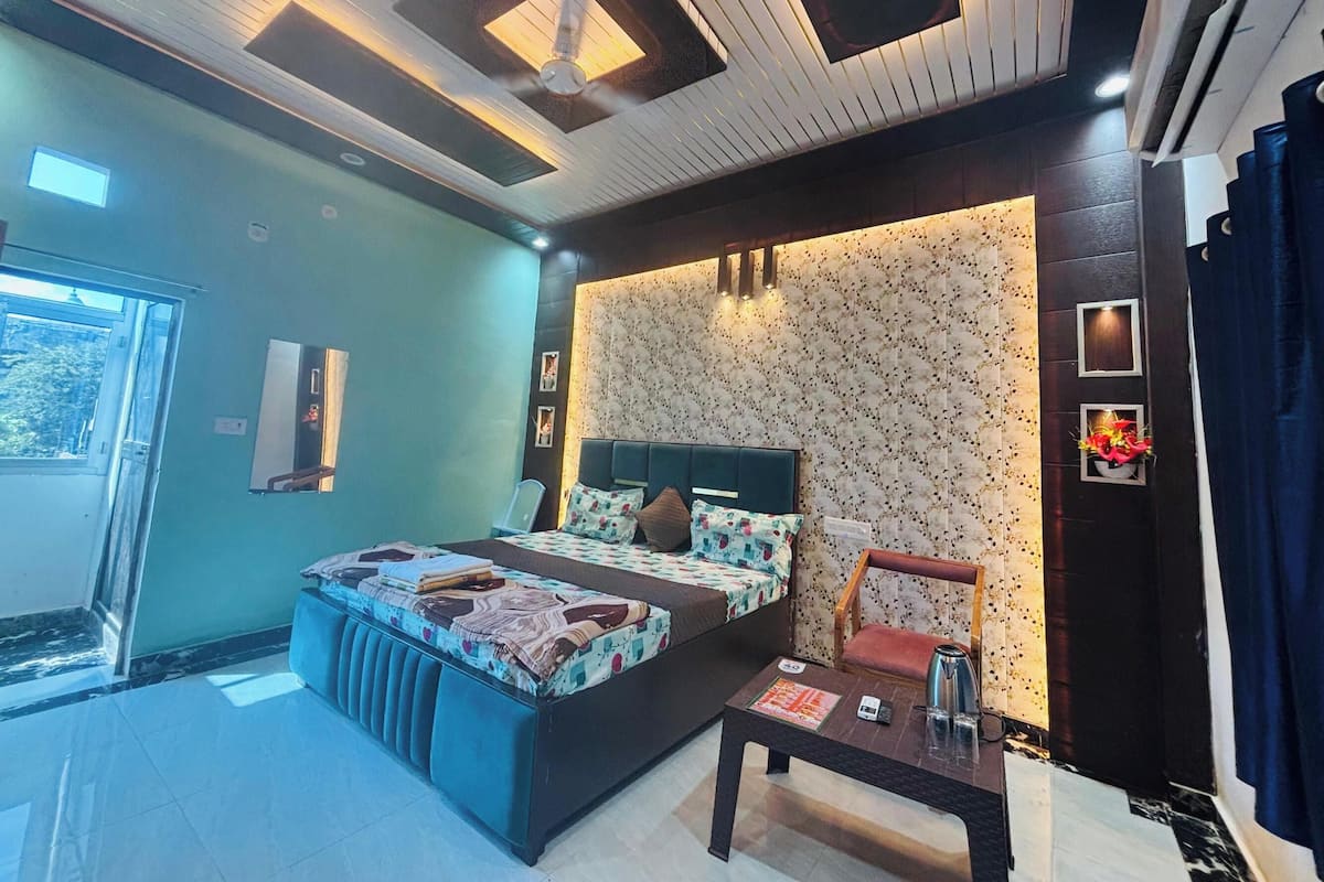 Un dormitorio moderno con una cama grande, una mesita de noche, una silla, un ventanal y un aire acondicionado de pared.