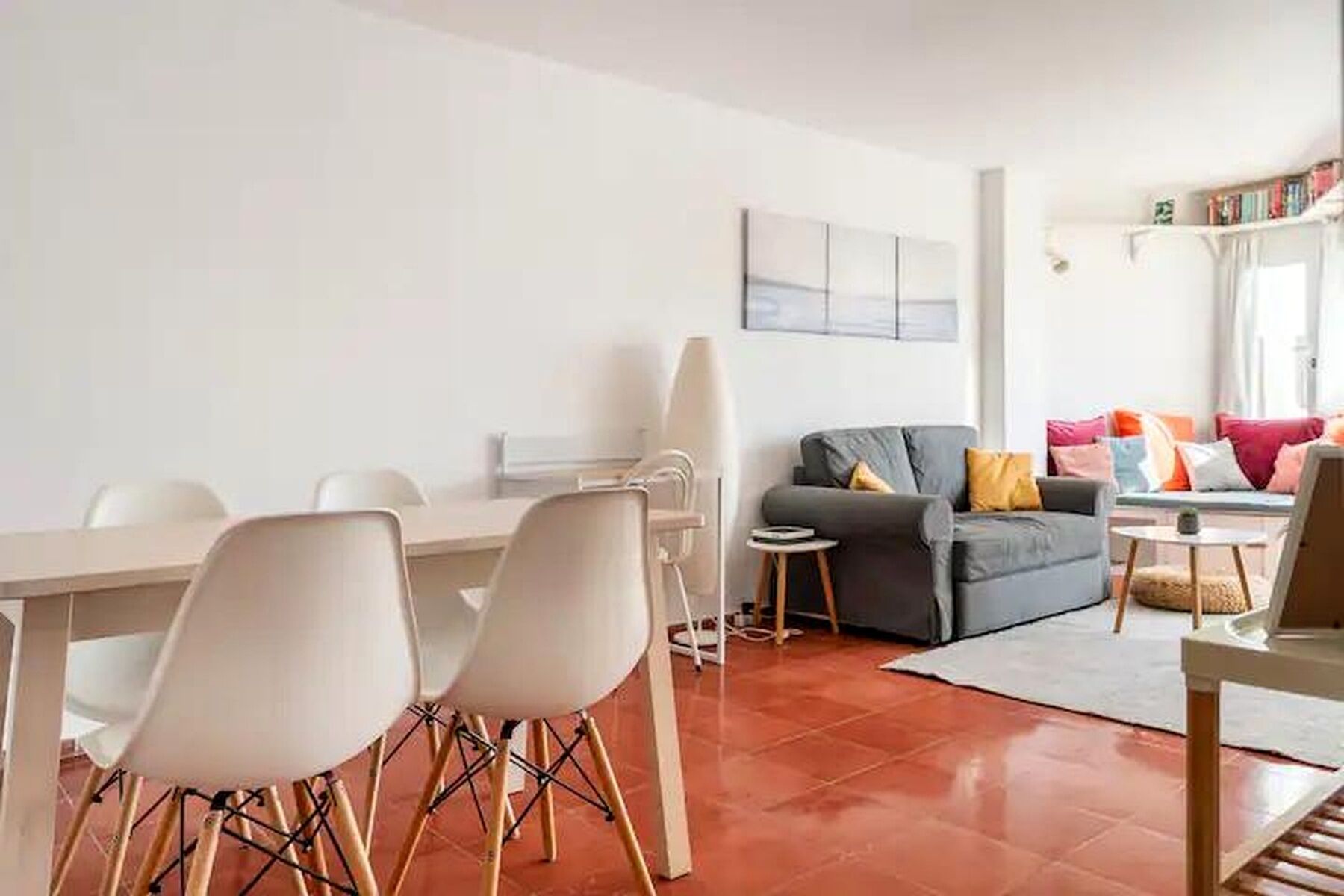 A modern living room with a dining area, a grey sofa, and a small table.