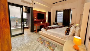 A hotel room with a bed, a desk, a TV, a balcony, and a window.